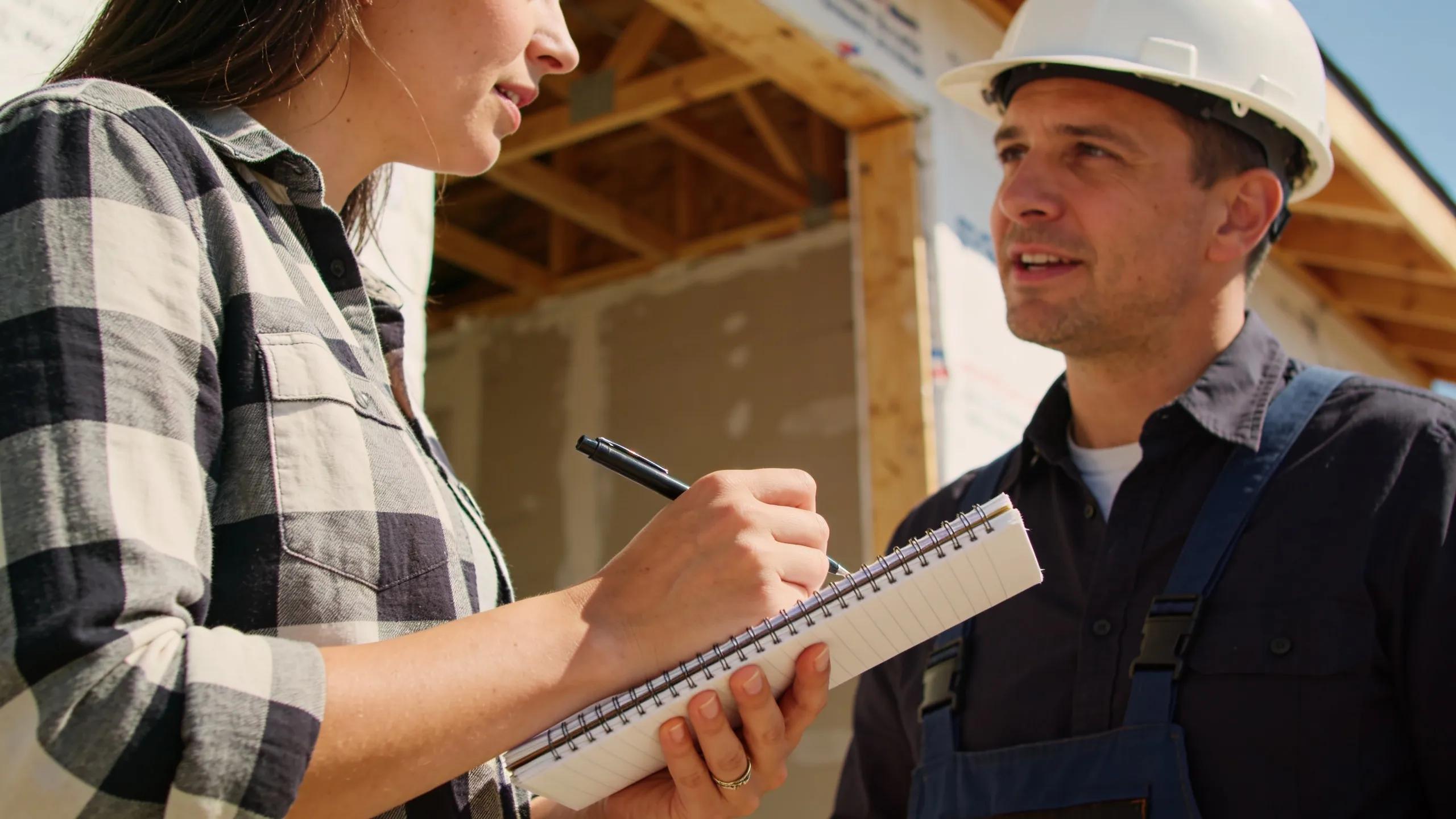 Homeowner consulting with a builder at a construction site, preparing questions about budget allowances.